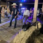 Scorcio di una festa con musica, balli e ospiti vestiti in stile country.