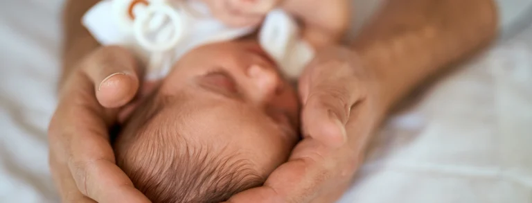 Neonato tra le mani amorevoli di un adulto